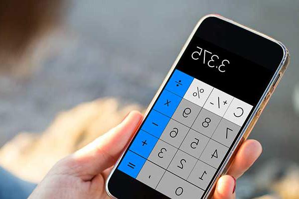 A person’s hand holds a calculator with a digital display. The display’s buttons are blue down the right side, white across the top, and a grey block between them. The readout shows a number: 3.375. 